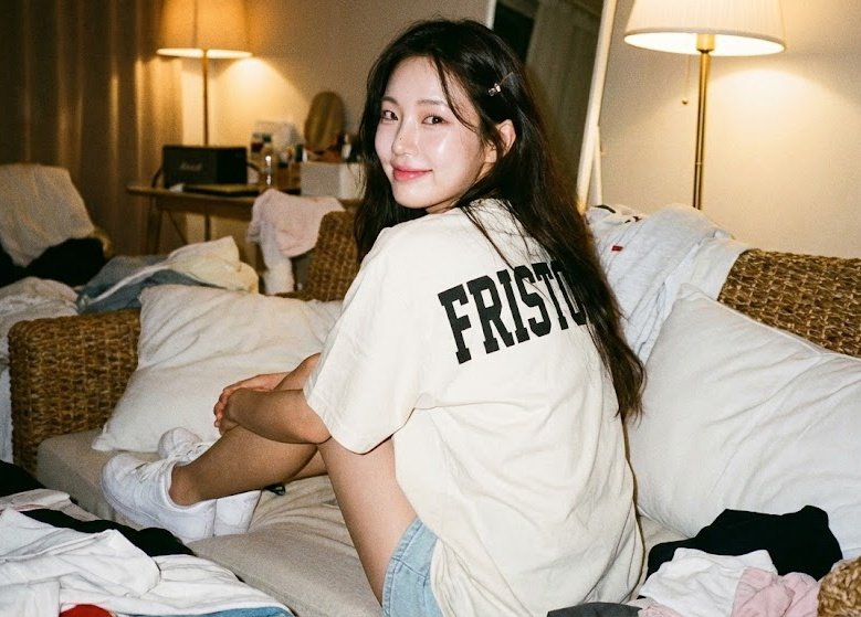 Девушка сидит спиной к зрителям на плетёном диване